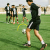 Soccer player practicing with a ball on a field, surrounded by teammates.